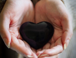 restorative yoga - cupped hands holding a heart shaped stone