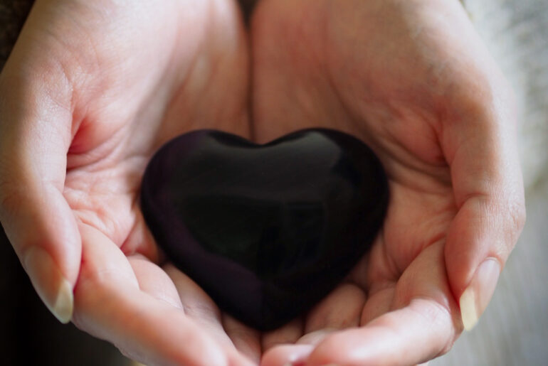 restorative yoga - cupped hands holding a heart shaped stone